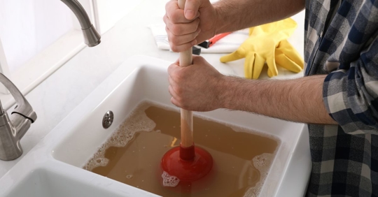 man plunging clogged drain