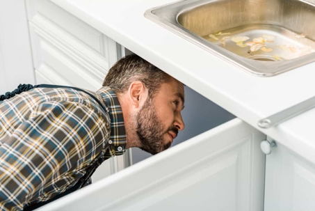 man looking under the sink