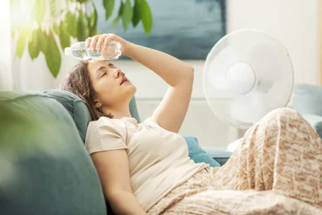 woman holding a cold bottle of water on her forehead